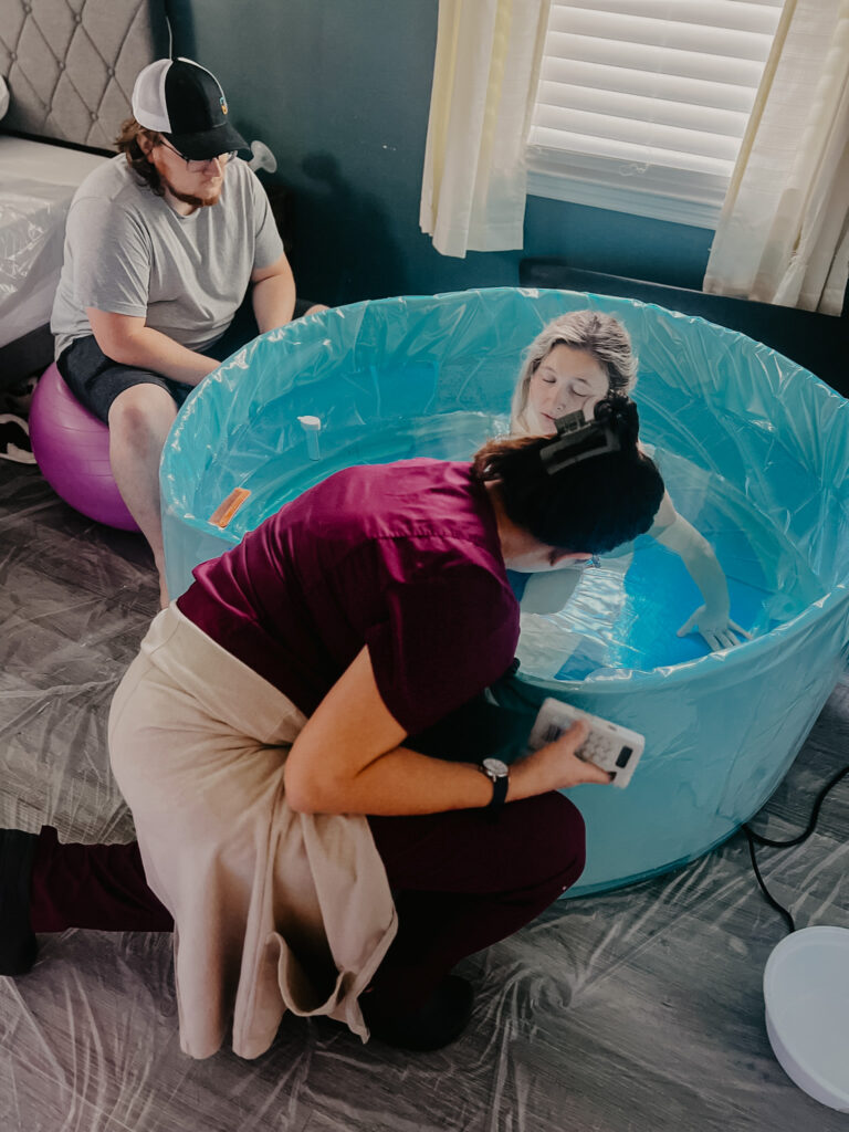 my midwife checking my sons heart rate as i labor in the birth pool