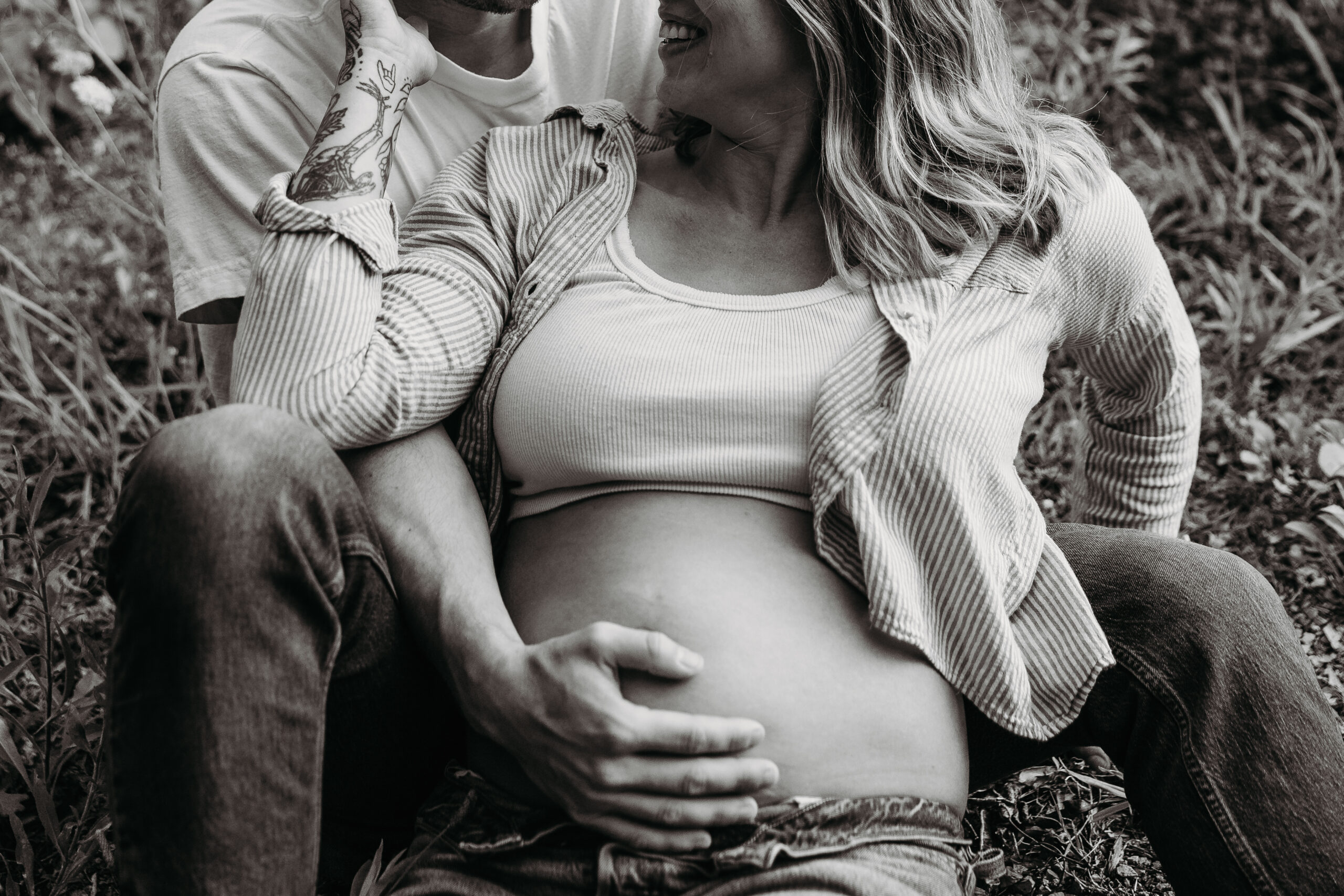 Maternity photoshoot of couple sitting in the grass