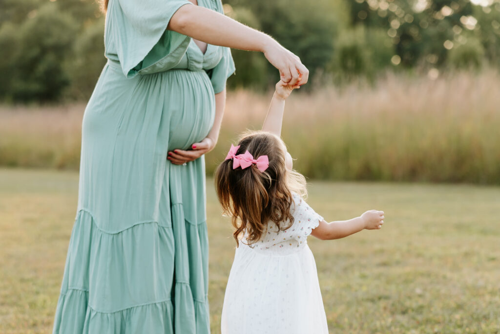 Mom and little girl twirling at west park in Westfield, indiana during maternity session