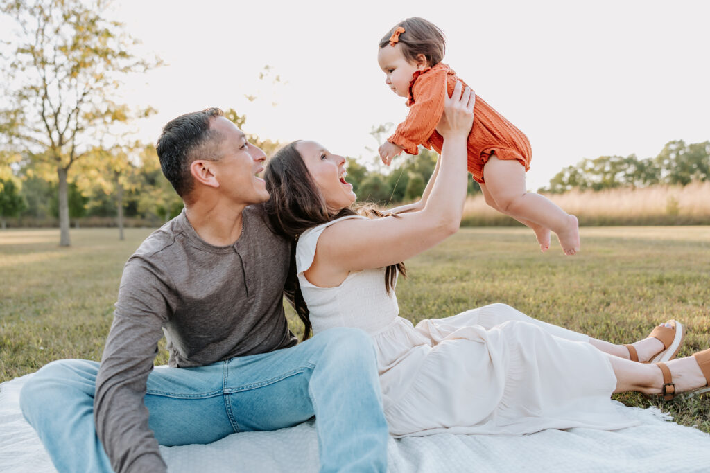 Parents at West Park in North Indy posed sitting on a blanket with their baby