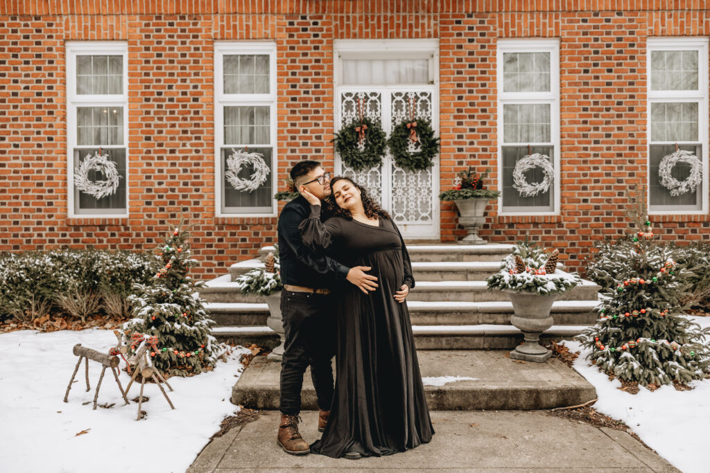 Maternity session at coxhall gardens where couple is in all black posed in front of a red brick architecture 