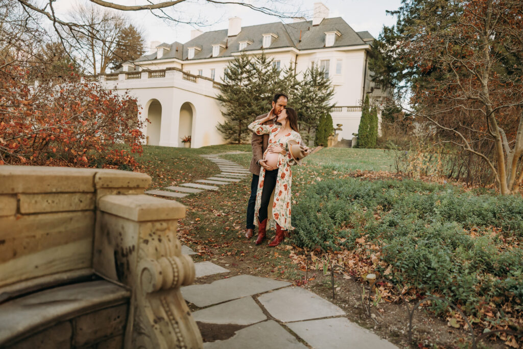 Couple with a western vibe maternity session posed in front of the Lilly house at Newfields in Indianapolis 